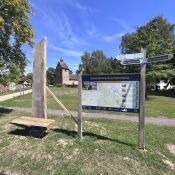 Neu aufgebaute Eichenstele mit Sitzbank neben der Wanderparkplatztafel in Kirchbrak.